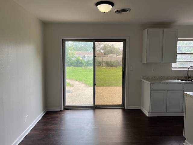 1302 Collins Dr, Pine Bluff, AR 71601 - unfurnished dining area featuring dark wood-style floors, baseboards, and a sink