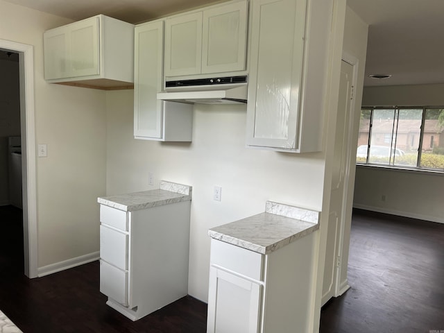 1302 Collins Dr, Pine Bluff, AR 71601 - kitchen with under cabinet range hood, dark wood-style floors, light countertops, white cabinets, and baseboards