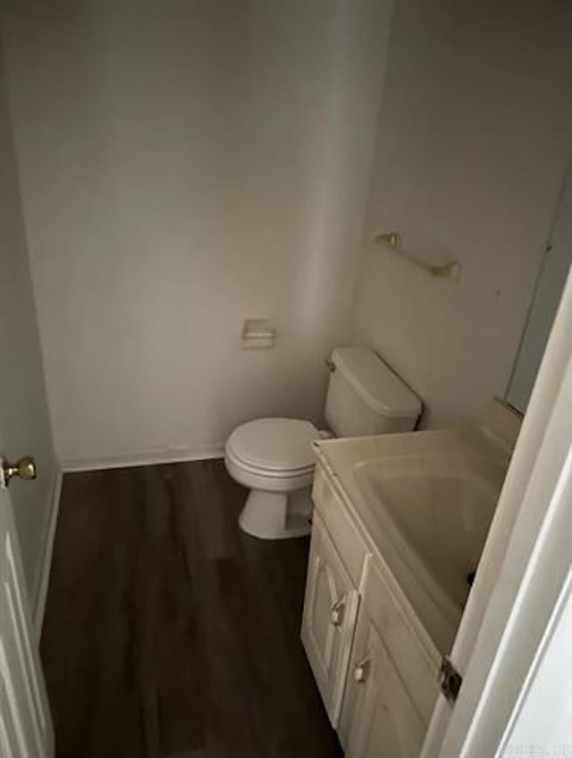 bathroom featuring vanity, toilet, wood finished floors, and baseboards