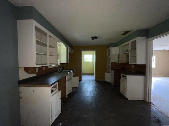 1602 Harmon Dr, Benton, AR 72015 - kitchen with open shelves, dark countertops, a sink, white cabinets, and dark tile patterned flooring