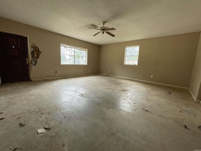 1602 Harmon Dr, Benton, AR 72015 - empty room featuring healthy amount of natural light, ceiling fan, concrete flooring, a textured ceiling, and baseboards