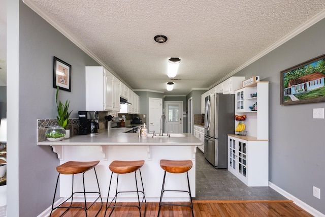 11 Blue Mountain Dr, Maumelle, AR 72113 - kitchen with stainless steel appliances, a peninsula, a kitchen bar, white cabinets, and crown molding