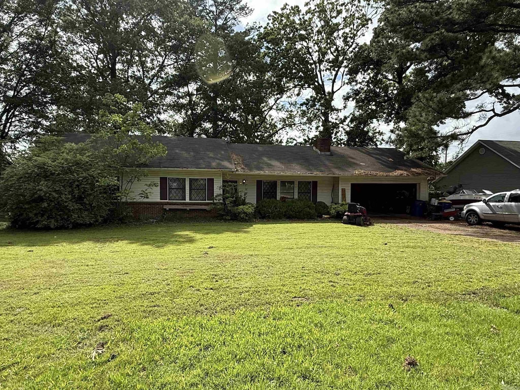 view of front of home featuring an attached garage, a chimney, a front yard, and driveway