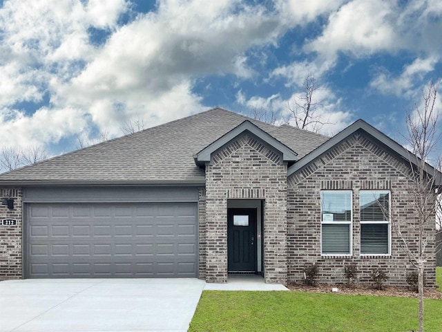 view of front of home featuring brick siding, concrete driveway, an attached garage, a shingled roof, and a front yard