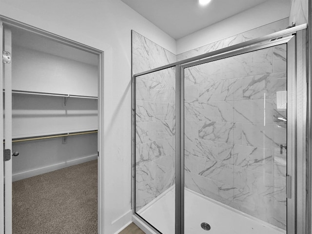 full bath featuring a marble finish shower and a walk in closet