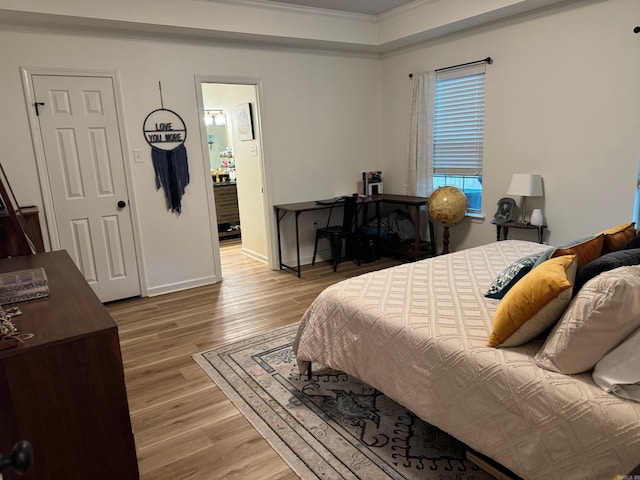 bedroom with crown molding, wood finished floors, and baseboards