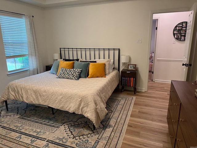bedroom with light wood-type flooring, baseboards, and ornamental molding