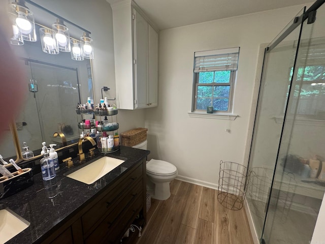 full bathroom with wood finished floors, a stall shower, toilet, vanity, and baseboards