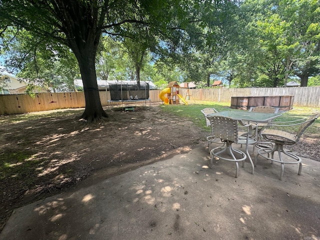 view of patio / terrace featuring a trampoline, a playground, and outdoor dining space