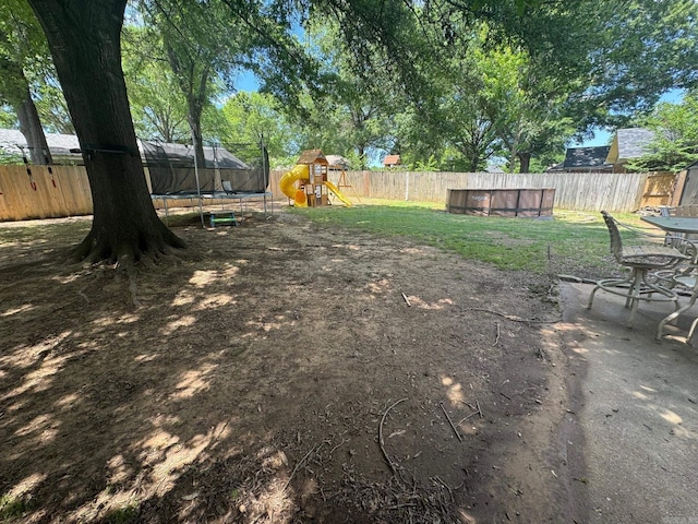 view of yard with a trampoline and a playground