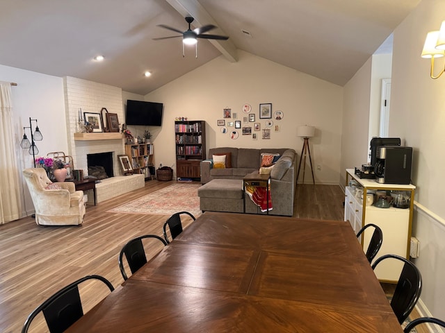 dining room featuring light wood-style floors, a ceiling fan, and a fireplace