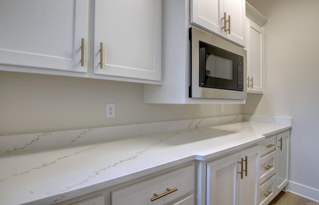 173 Maumelle Valley Dr, Maumelle, AR 72113 - kitchen featuring built in microwave, white cabinets, and light stone counters