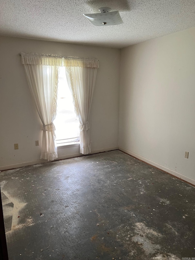 empty room featuring a textured ceiling and baseboards