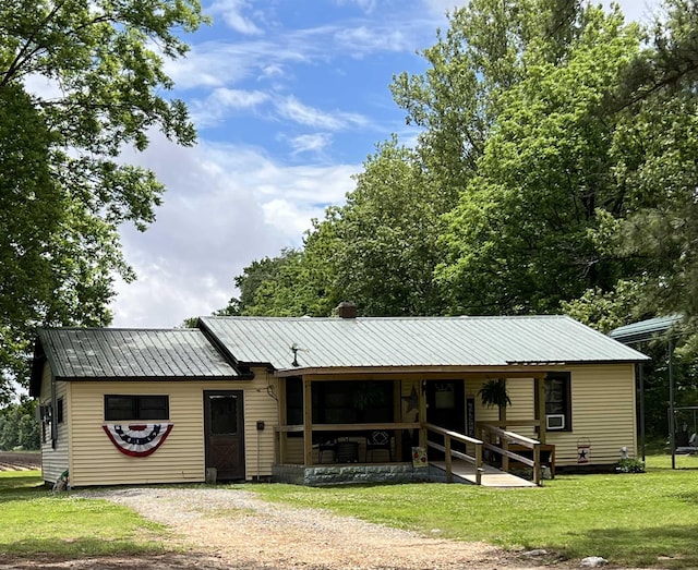 view of front facade with metal roof, a front lawn, and driveway