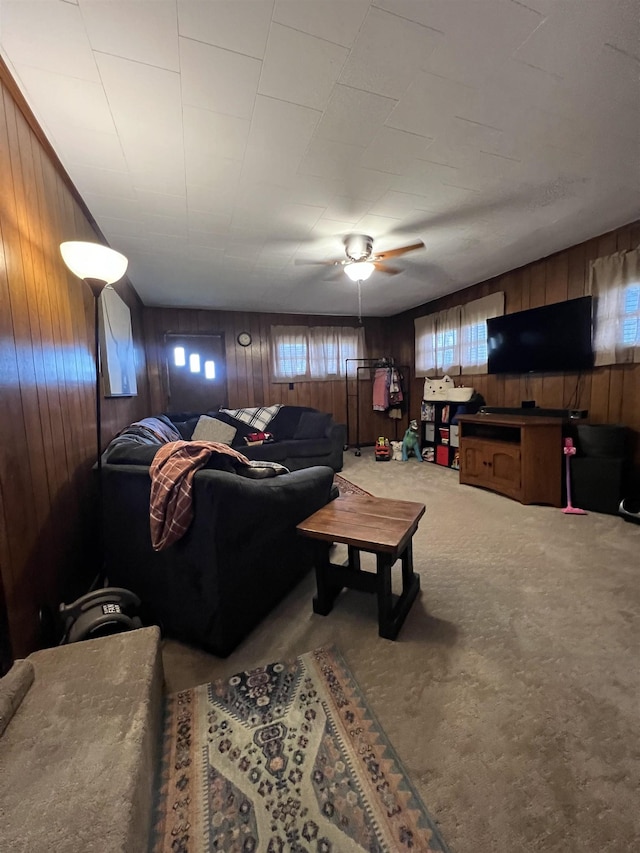 living room featuring wooden walls, ceiling fan, and carpet