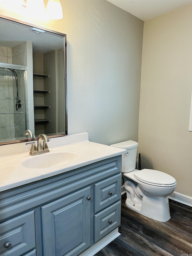 full bath with a stall shower, toilet, vanity, and wood finished floors
