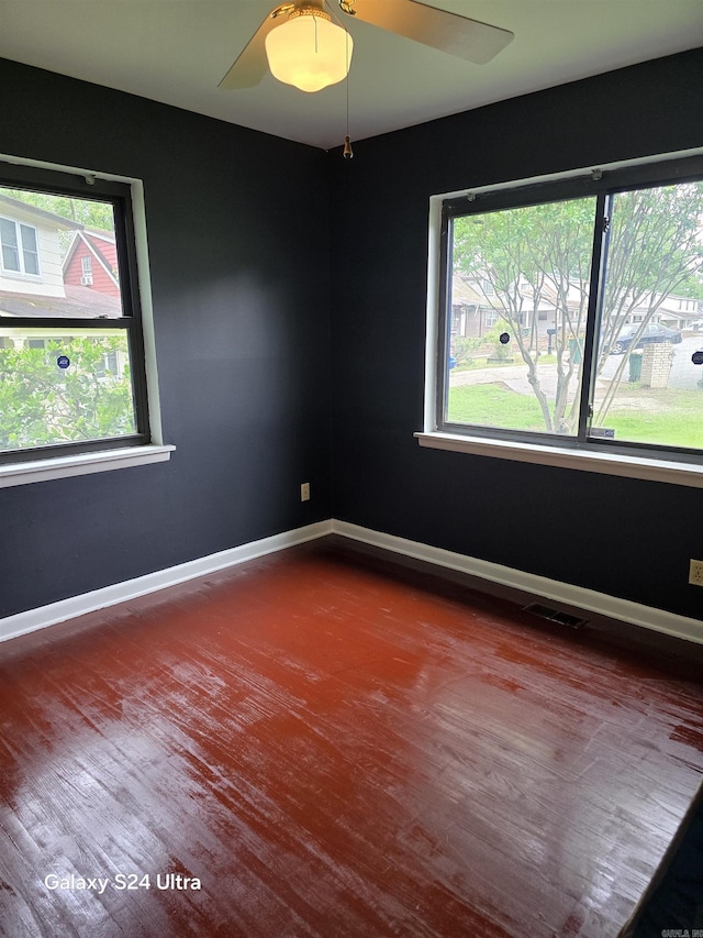 unfurnished room featuring dark wood-style flooring, ceiling fan, and baseboards