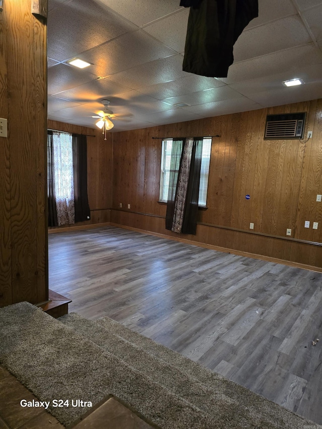 unfurnished room with wood finished floors, a ceiling fan, and wooden walls