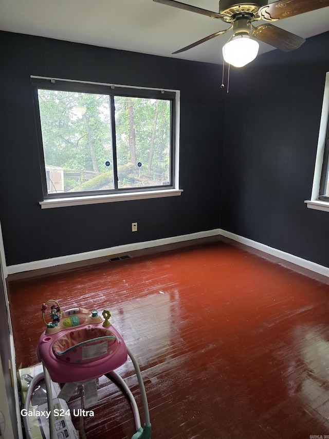 spare room with wood finished floors, plenty of natural light, baseboards, and a ceiling fan
