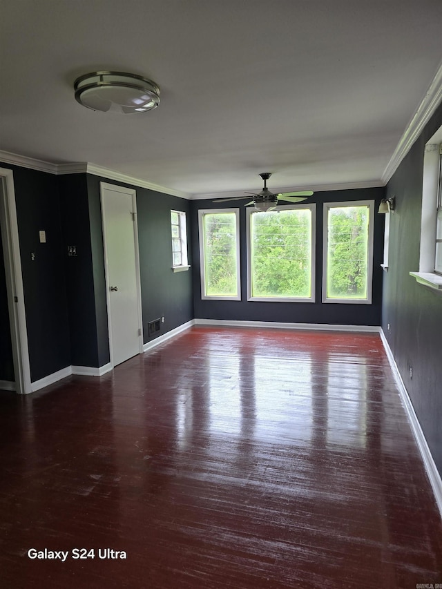 empty room featuring crown molding, ceiling fan, wood finished floors, and baseboards