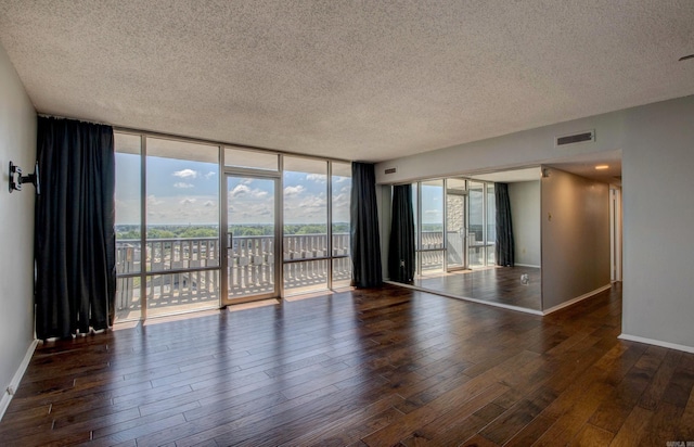 700 E 9th St Unit 9A, Little Rock, AR 72202 - unfurnished room featuring a textured ceiling, hardwood / wood-style floors, healthy amount of natural light, baseboards, and a wall of windows