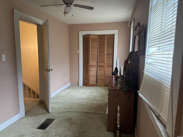 carpeted bedroom with a closet, a textured ceiling, ceiling fan, and baseboards