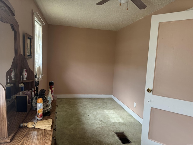 unfurnished bedroom with carpet, baseboards, a textured ceiling, and a ceiling fan