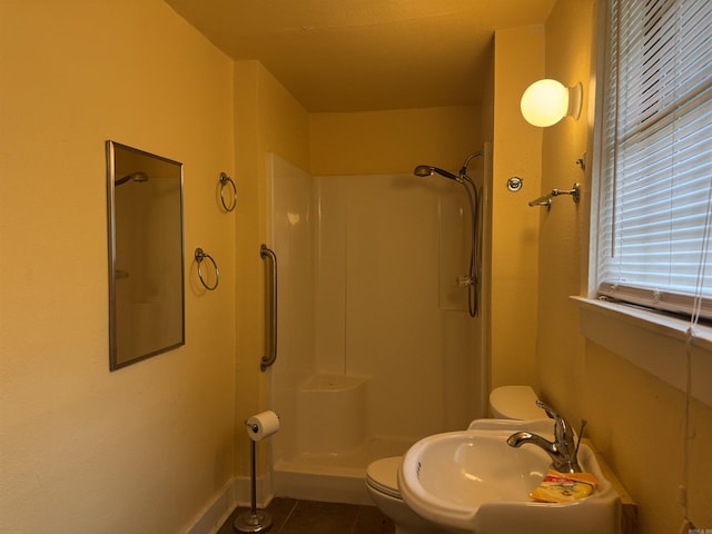 bathroom featuring a shower, tile patterned flooring, toilet, a sink, and baseboards