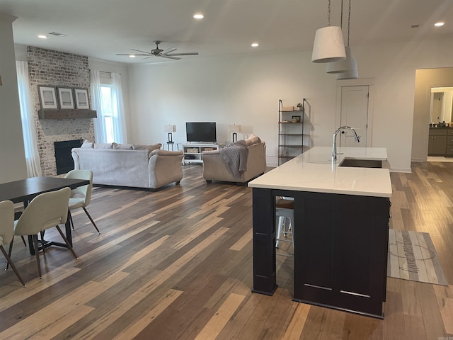 2009 Berkshire Dr, Benton, AR 72019 - kitchen featuring dark wood-type flooring, a sink, a ceiling fan, a brick fireplace, and recessed lighting