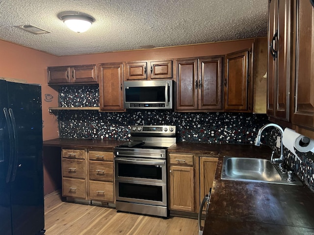 600 King St, Searcy, AR 72143 - kitchen with appliances with stainless steel finishes, a sink, dark countertops, light wood-style floors, and a textured ceiling