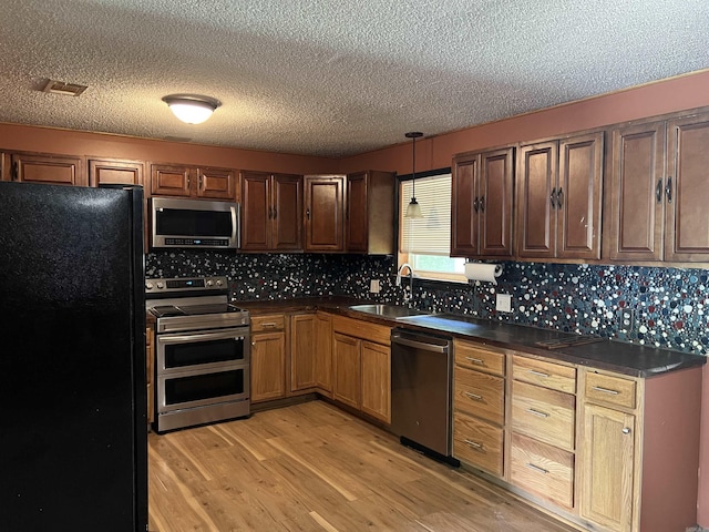 600 King St, Searcy, AR 72143 - kitchen with stainless steel appliances, a sink, dark countertops, light wood-style floors, and a textured ceiling