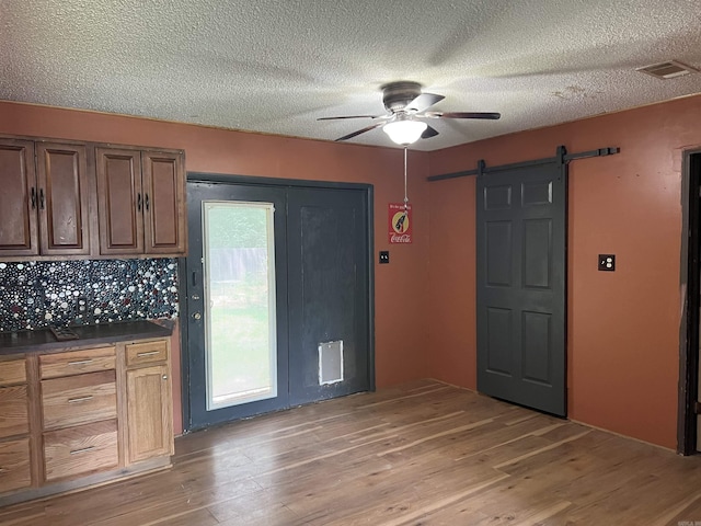 600 King St, Searcy, AR 72143 - kitchen featuring a ceiling fan, a barn door, light wood-style flooring, dark countertops, and a textured ceiling