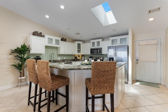 110 Jamison Ln, Hot Springs, AR 71913 - kitchen with appliances with stainless steel finishes, light tile patterned floors, a breakfast bar, lofted ceiling, and a skylight