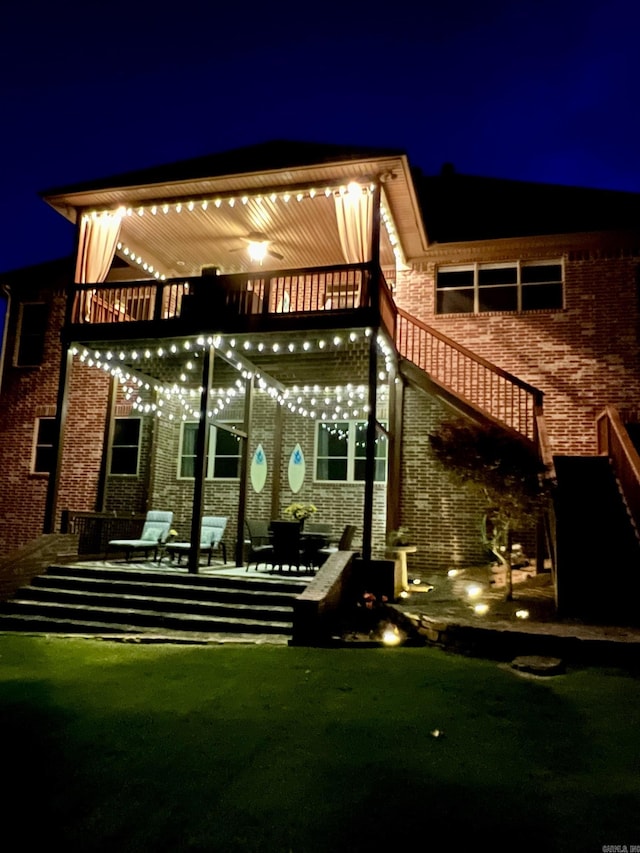 32 Bronte Ct, Little Rock, AR 72223 - back of house at twilight with brick siding, stairs, and a balcony
