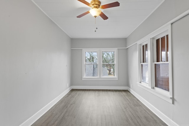 empty room with wood finished floors, baseboards, and ceiling fan