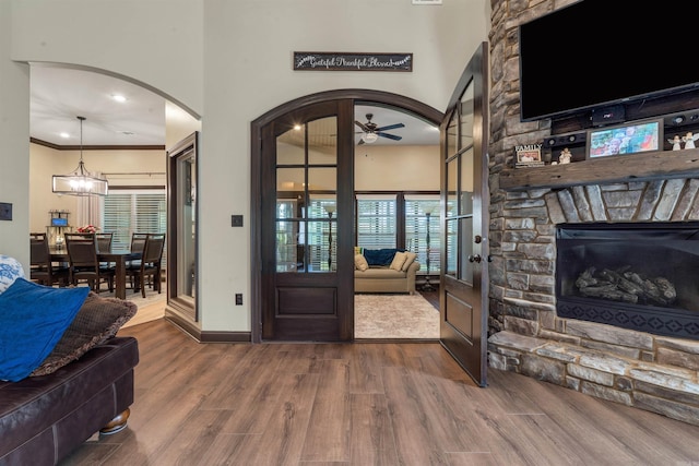 living room with a ceiling fan, wood finished floors, arched walkways, plenty of natural light, and crown molding