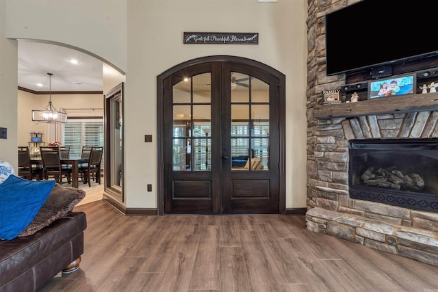 entrance foyer featuring baseboards, arched walkways, wood finished floors, french doors, and ornamental molding