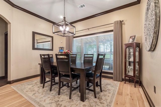 dining area with arched walkways, crown molding, a chandelier, light wood finished floors, and baseboards