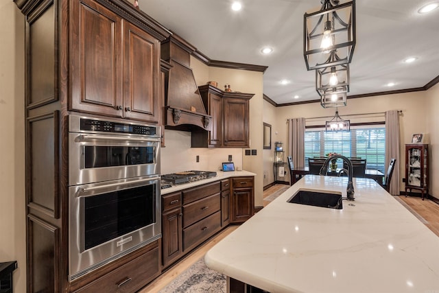 kitchen with appliances with stainless steel finishes, crown molding, a sink, custom range hood, and dark brown cabinetry