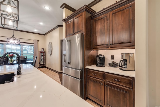 kitchen featuring high end refrigerator, crown molding, a sink, recessed lighting, and baseboards