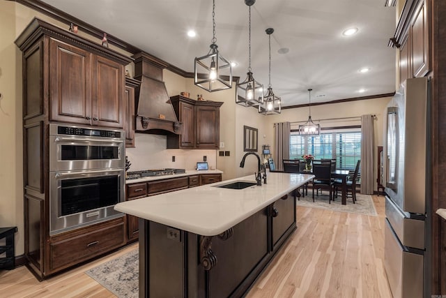 kitchen featuring appliances with stainless steel finishes, a sink, premium range hood, light countertops, and dark brown cabinets