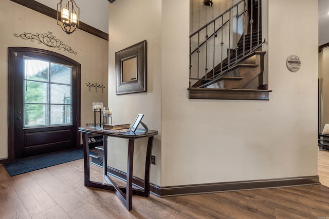 foyer entrance featuring wood finished floors, baseboards, a towering ceiling, and stairs
