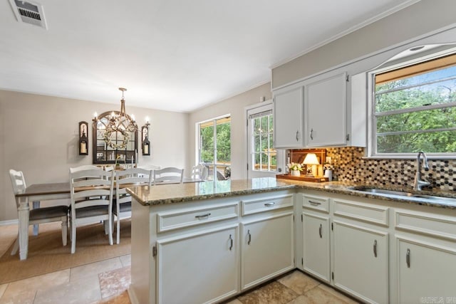 3311 Hazy Ridge Ct, Little Rock, AR 72227 - kitchen with a peninsula, a sink, a chandelier, decorative backsplash, and light stone counters