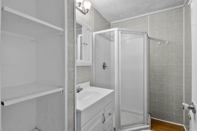 503 N Walnut St, Searcy, AR 72143 - bathroom featuring tile walls, vanity, a textured ceiling, a shower stall, and wood finished floors