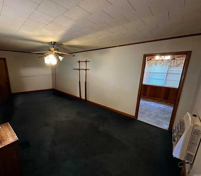 spare room featuring dark carpet, a ceiling fan, baseboards, and ornamental molding