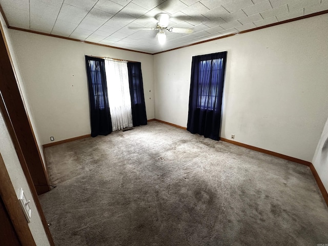 spare room with crown molding, carpet flooring, ceiling fan, and baseboards