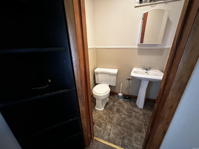 half bath featuring toilet and wainscoting