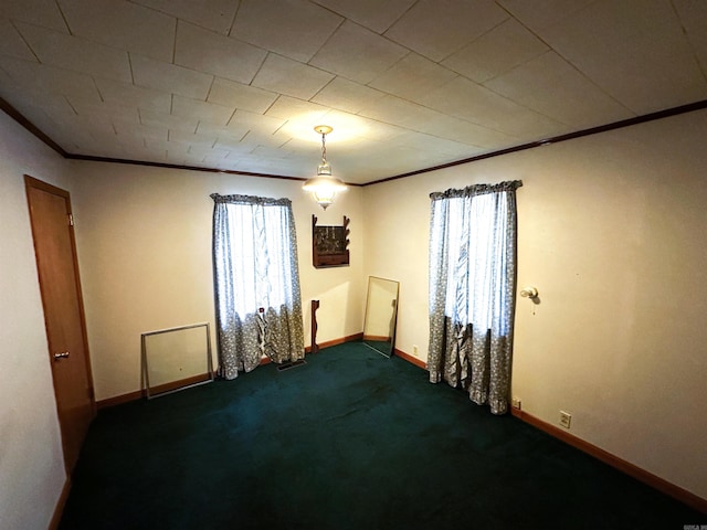 spare room featuring crown molding, baseboards, and dark carpet