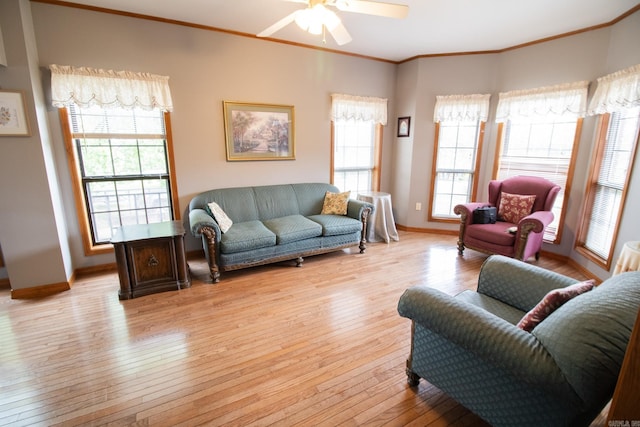 living area featuring light wood-style flooring, a ceiling fan, ornamental molding, and baseboards