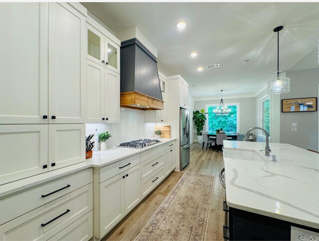 816 Nature Way, Benton, AR 72019 - kitchen with stainless steel appliances, backsplash, light wood finished floors, hanging light fixtures, and white cabinetry